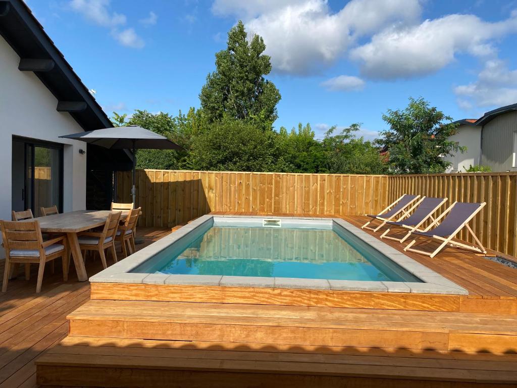 una piscina su una terrazza con sedie e tavolo di LUTZY Maison moderne au calme piscine a La Teste-de-Buch