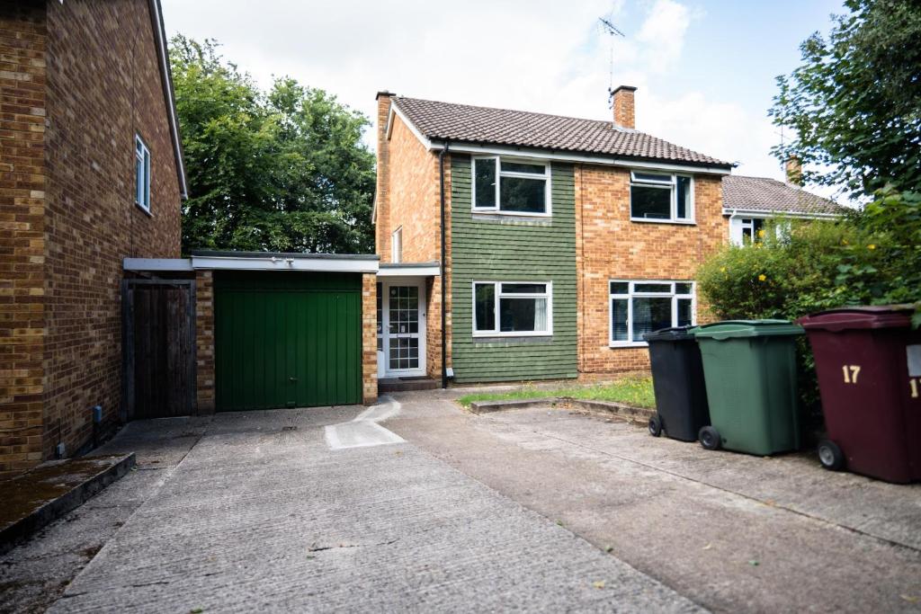 a house with a green garage and two trash cans at Charming 6-Bed House in Reading in Reading