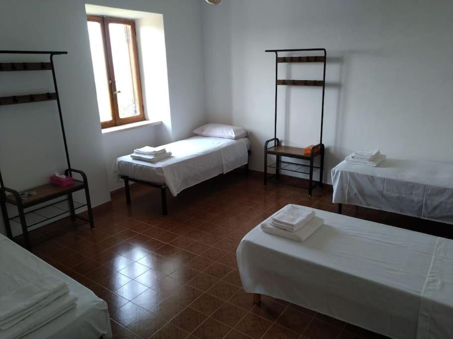 een kamer met 2 bedden en 2 stoelen. bij Casetta con camino per pellegrini e camminatori in Cantalice