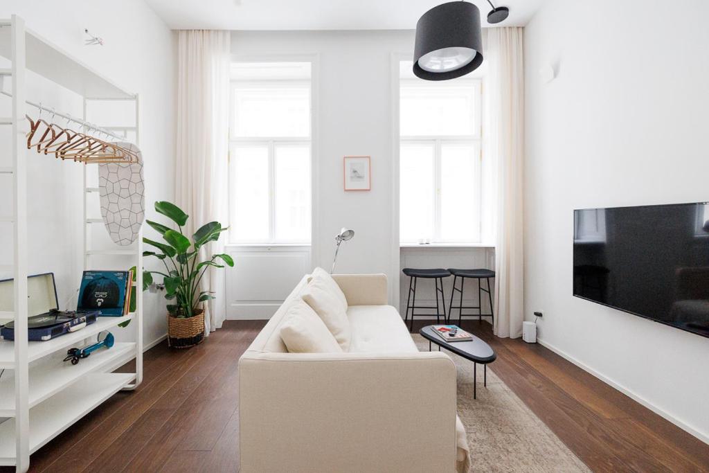 a living room with a white couch and a tv at Design Apartment Spittelberg - 7th district - contactless checkin in Vienna