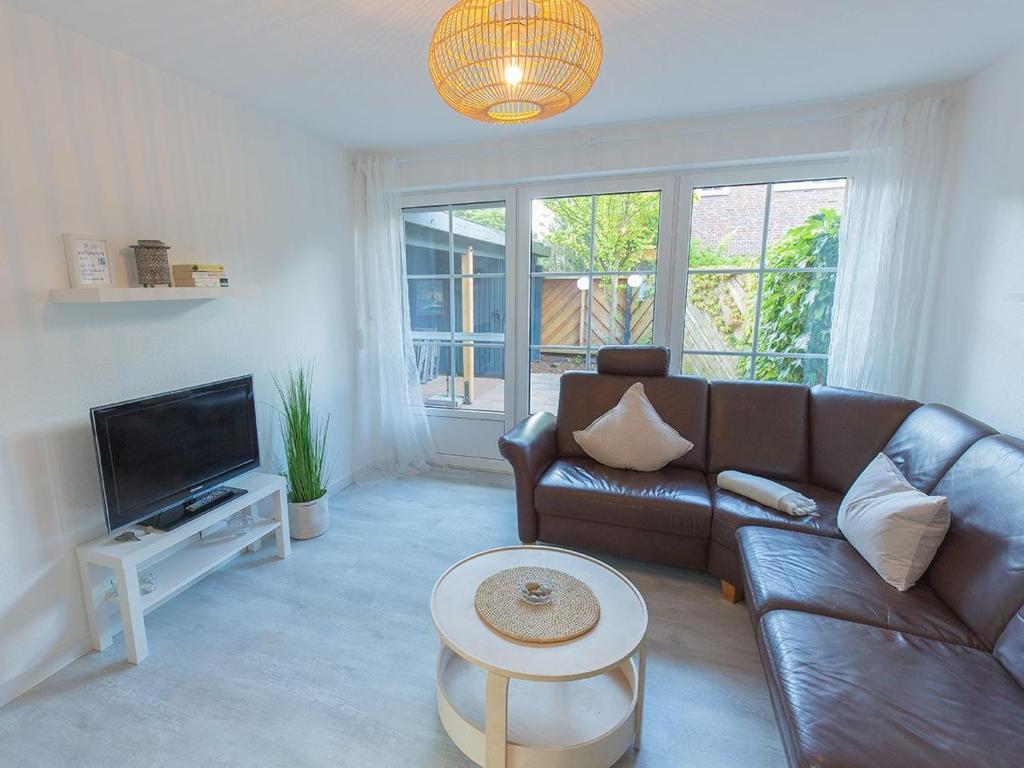 un salon avec un canapé en cuir et une télévision dans l'établissement Ferienhaus Lüttjes Strandhus, FeWo Vermittlung Nordsee, à Dangast