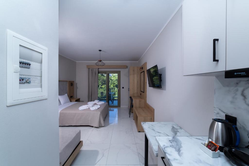 a white room with a bed and a kitchen at Sky View Suites Kefalonia in Vóvikes