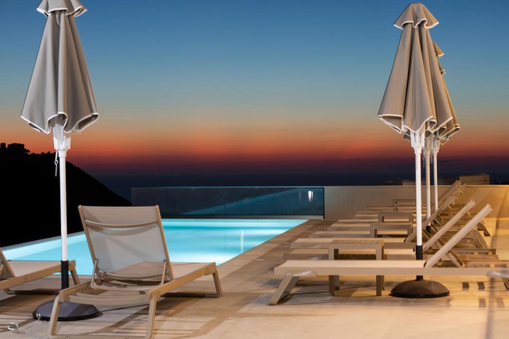 a row of chairs and umbrellas on a swimming pool at Sky View Suites Kefalonia in Vóvikes