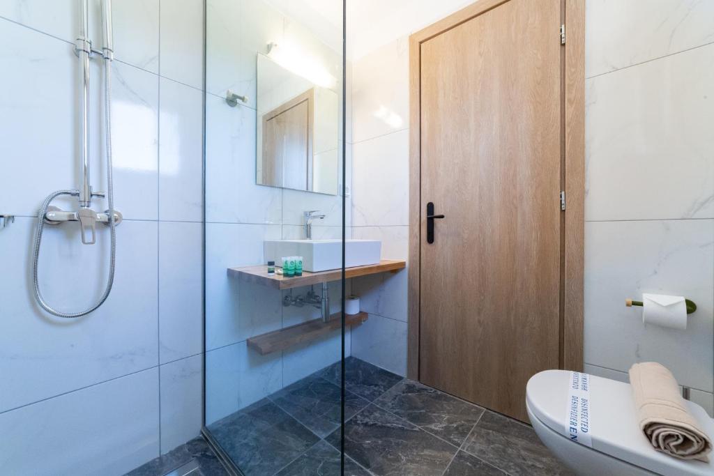 a bathroom with a shower and a toilet and a sink at Sky View Suites Kefalonia in Vóvikes
