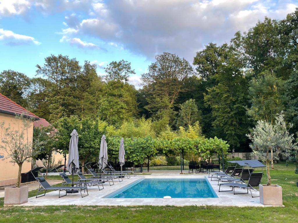 a swimming pool with lawn chairs and umbrellas at Sweethome – La Jacqueminière in Courtenay