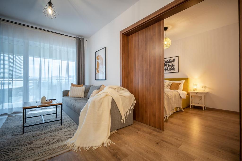 ein Wohnzimmer mit einem Sofa und einem Bett in der Unterkunft Lakeview Modern Condo-Tennis, Parking, Balcony in Cluj-Napoca
