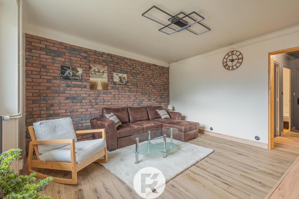 a living room with a leather couch and a brick wall at R'Apparts T4 Urban Loft in Noyarey