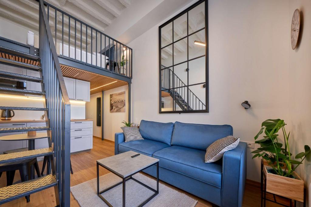 a living room with a blue couch and a staircase at Queen Barbora Central Lofts in Kaunas