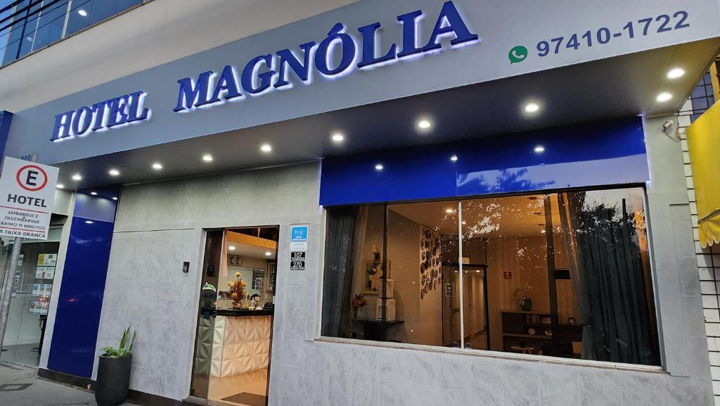 a store with a blue sign on the side of a building at Hotel Magnólia in São João da Boa Vista