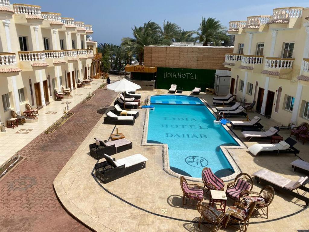 Lidia Dahab Hotel and Restaurant في دهب: مسبح فيه جلسات وكراسي في منتجع