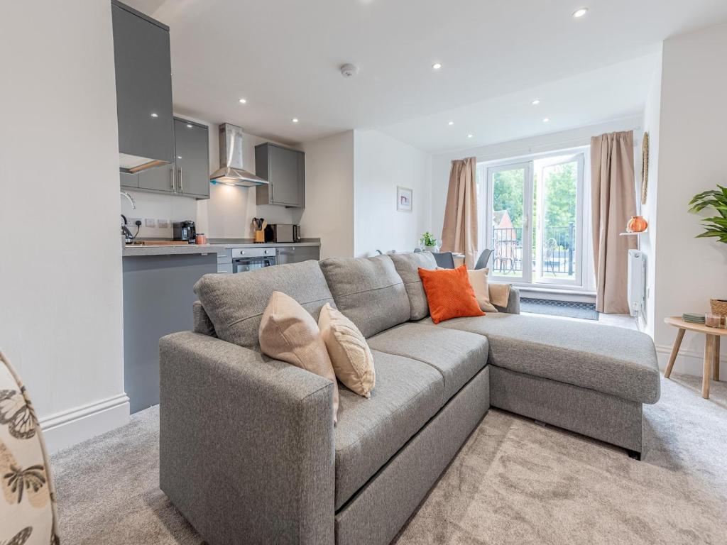 ein Wohnzimmer mit einem grauen Sofa und einer Küche in der Unterkunft Pass the Keys Stunning Apartment with Terrace in Telford
