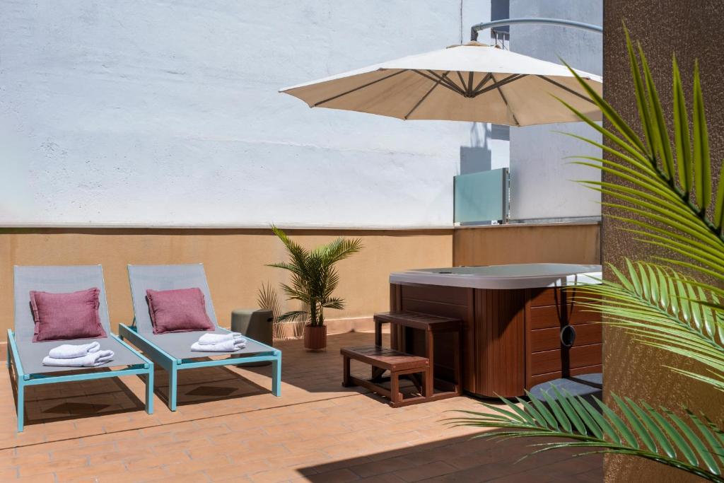 eine Terrasse mit 2 Stühlen, einem Tisch und einem Sonnenschirm in der Unterkunft Suites Maestranza - Herrería by Magno Apartments in Sevilla