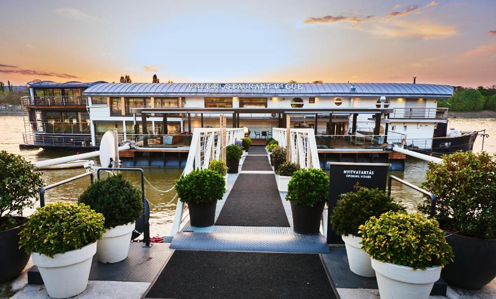 a boat on the water with potted plants in front of it at Vogue Boat Apartments in Budapest