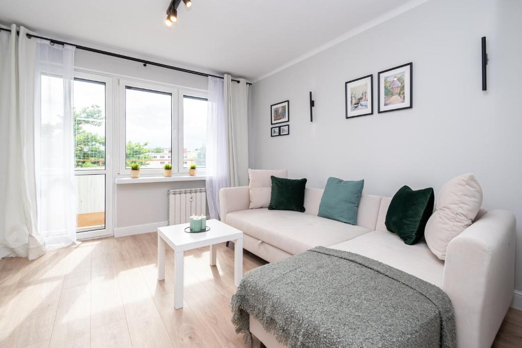 a white living room with a couch and a table at Apartament Nowy Świat 15-17 in Kalisz