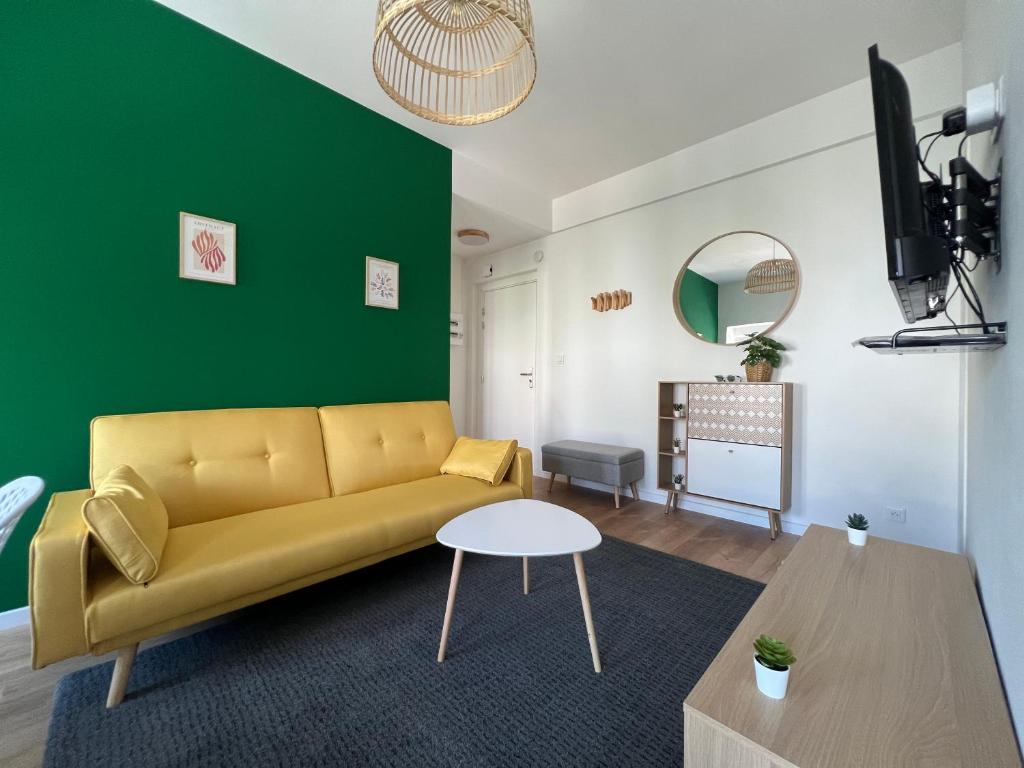 a living room with a yellow couch and a green wall at La Cour de Clemenceau in Montbéliard