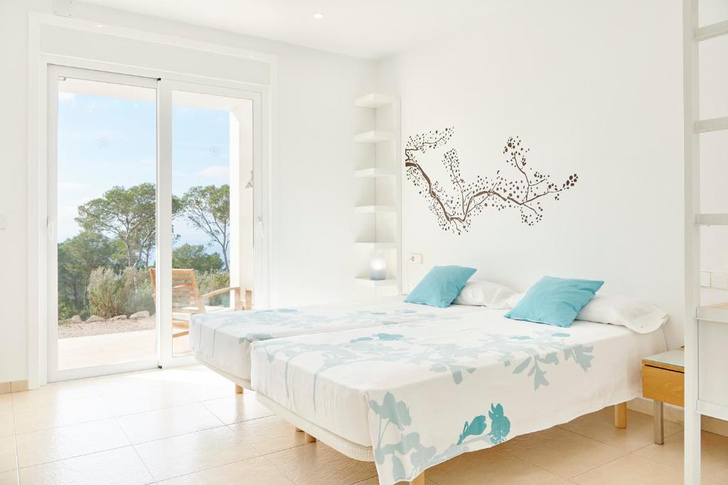 a white bedroom with a large bed with blue pillows at Villa Ses Abelles in San Jose
