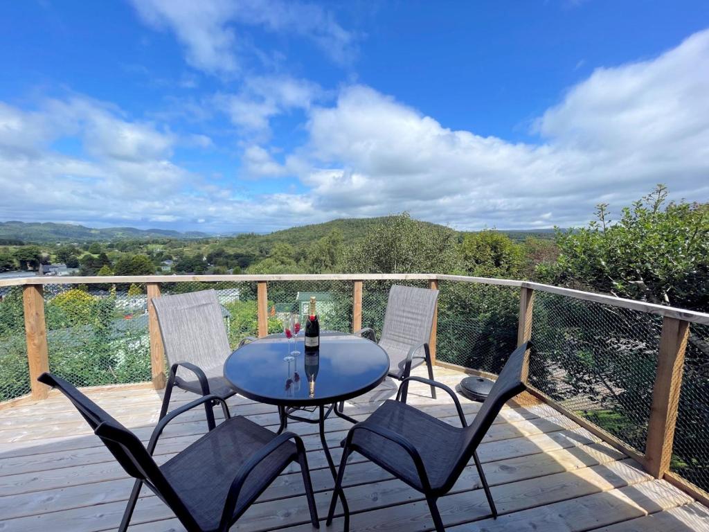 una mesa y 4 sillas en una terraza de madera en Pass the Keys Gorgeous Kippford Home With Outstanding Views, en Kippford