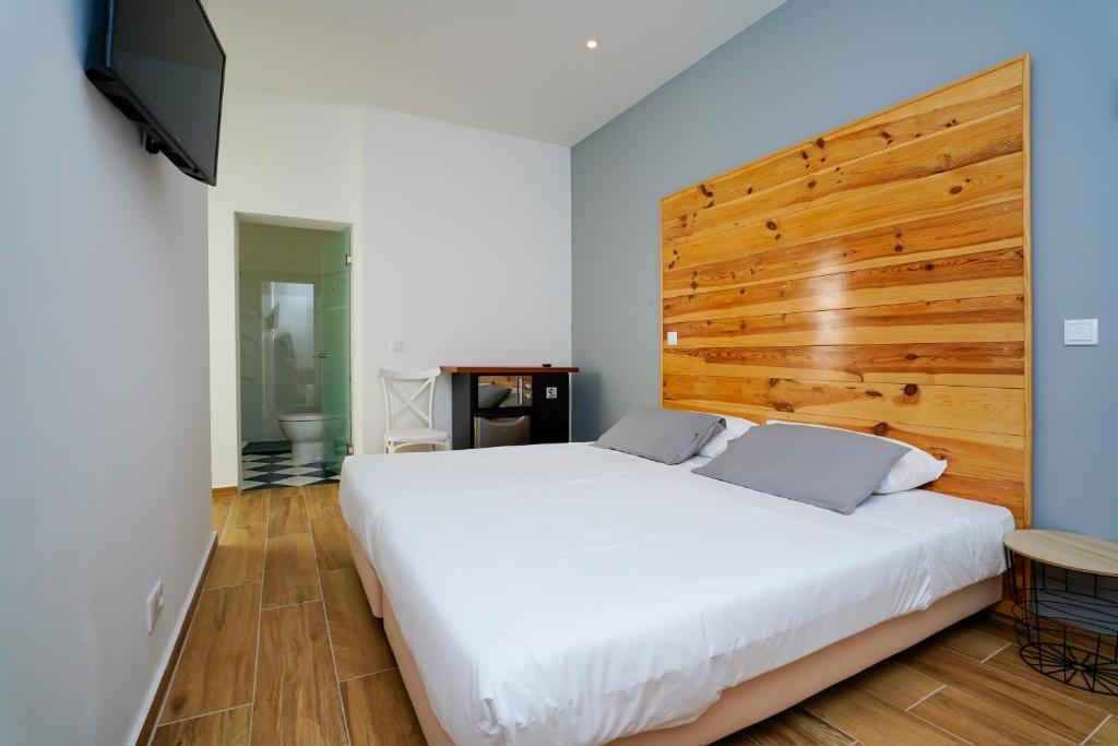 um quarto com uma grande cama branca e uma cabeceira em madeira em Alameda Guesthouse by Boutique Taipas Garagem para motos em Portimão