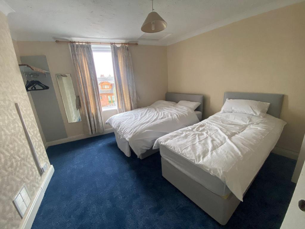 1 dormitorio con 2 camas y ventana en Victoria Guest House en Stoke on Trent