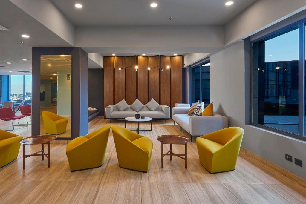 sala de estar con sillas amarillas y sofá en City Express Plus by Marriott Interlomas, en Ciudad de México