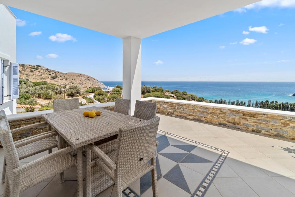 einen Tisch und Stühle auf einem Balkon mit Meerblick in der Unterkunft Seaside & Modern Flats near Chora in Steniaí