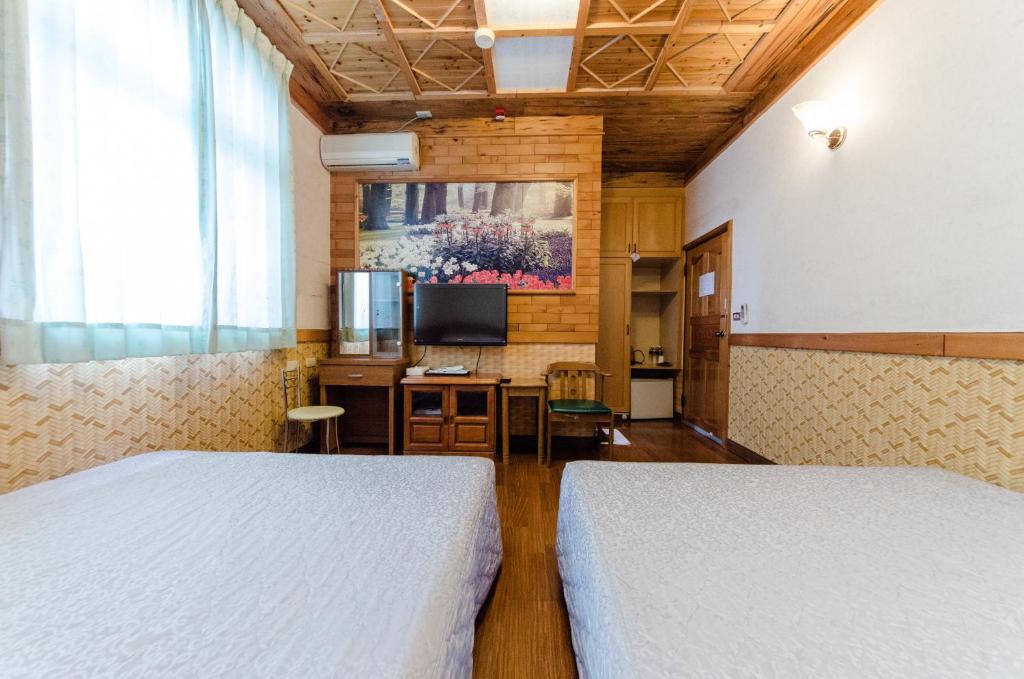 a bedroom with two beds and a television in it at Donglifang B&amp;B in Guanshan