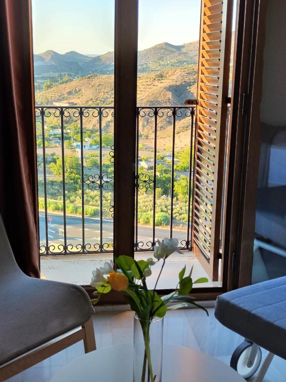 a vase with flowers on a table in front of a window at Balcón de la Villa in Priego de Córdoba