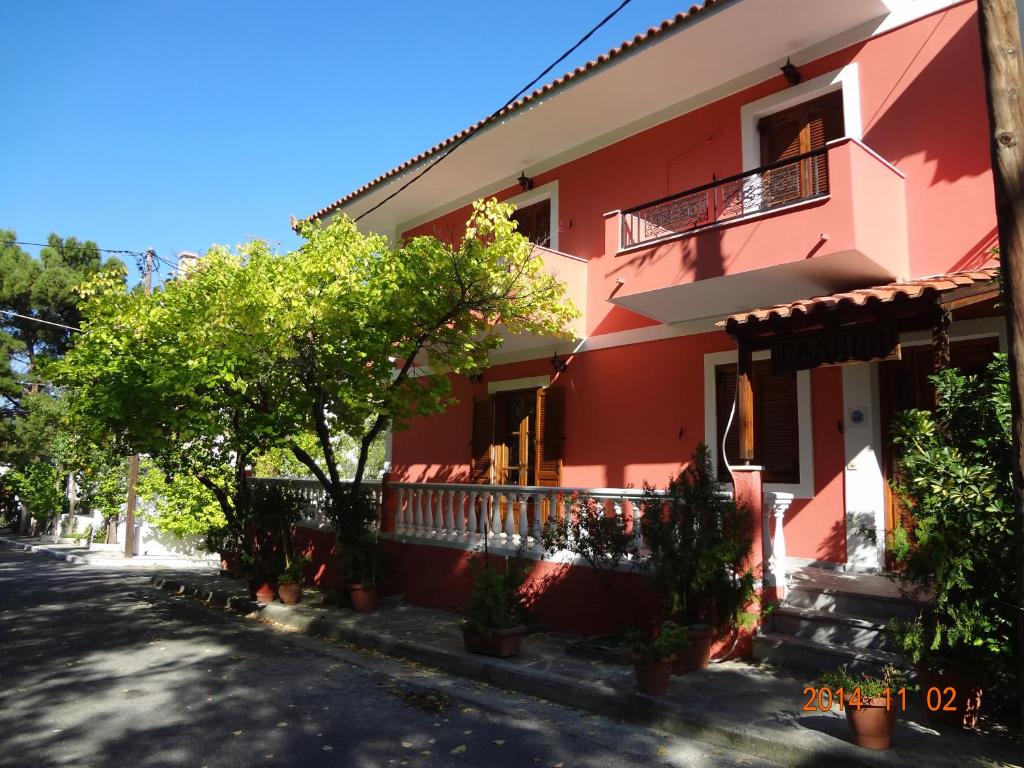 un edificio rosso con alberi di fronte di Villa Mary Galini a Iraion