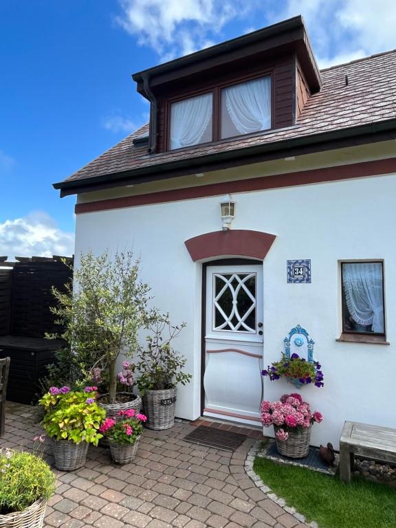 ein weißes Haus mit Topfpflanzen auf einer Terrasse in der Unterkunft Haus Boy Jensen Wohnung Dünenblick in Wenningstedt-Braderup