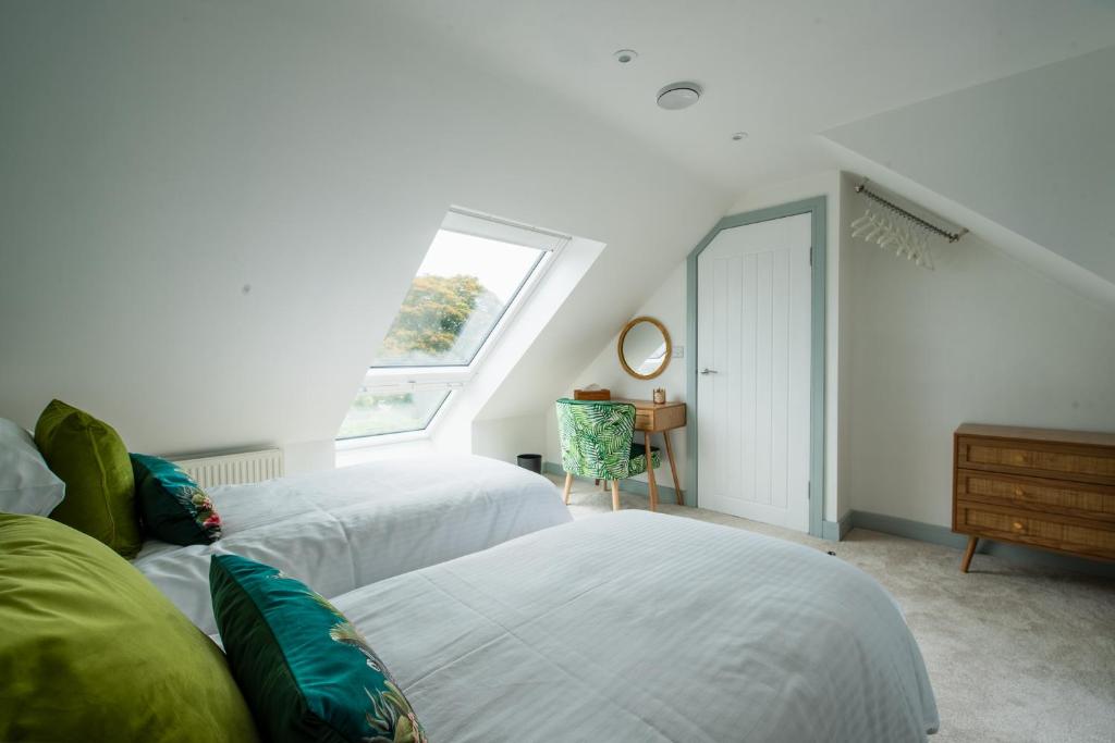 a attic bedroom with two beds and a window at Maycliffe in Shanklin