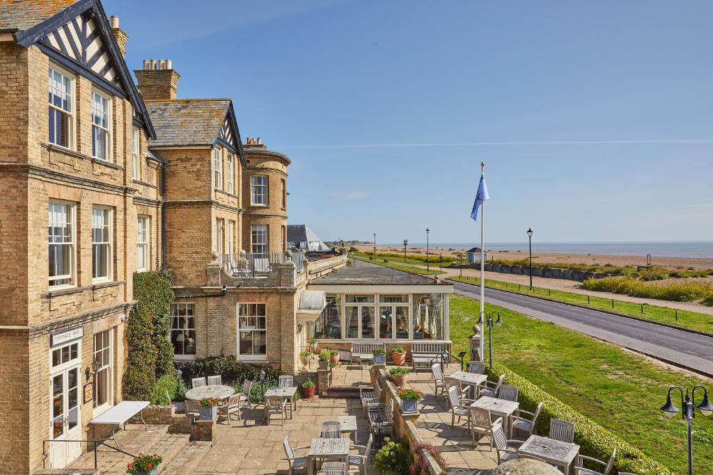 ein Gebäude mit Tischen und Stühlen davor in der Unterkunft Wentworth Hotel in Aldeburgh