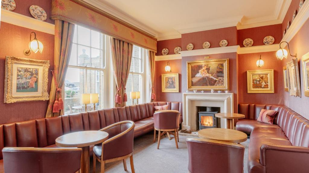 a waiting room with leather furniture and a fireplace at Wentworth Hotel in Aldeburgh