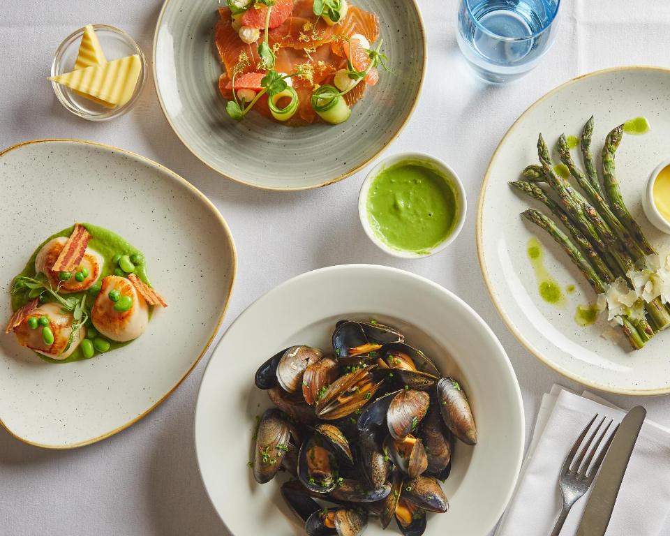 a table topped with plates of food with mussels and vegetables at Wentworth Hotel in Aldeburgh