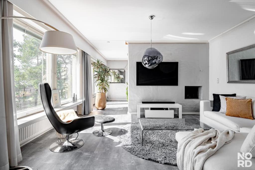 ein weißes Wohnzimmer mit einem Stuhl und einem Sofa in der Unterkunft Westend Luxury Spa House in Espoo