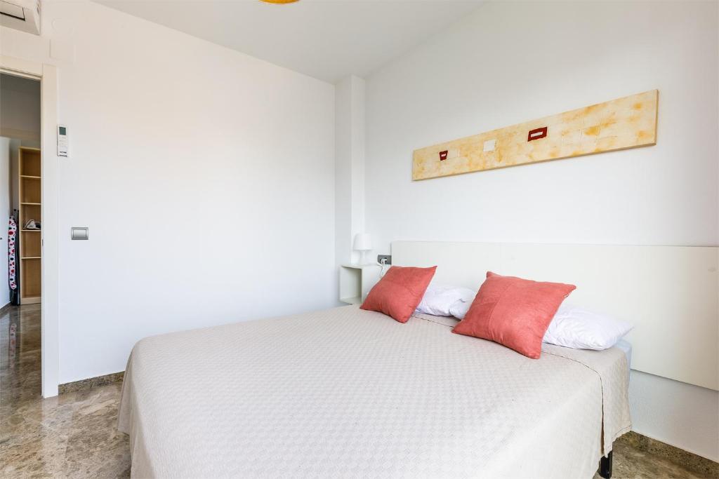 1 dormitorio con 1 cama blanca y 2 almohadas rojas en A&N Torreon del Carmen, en Algarrobo Costa