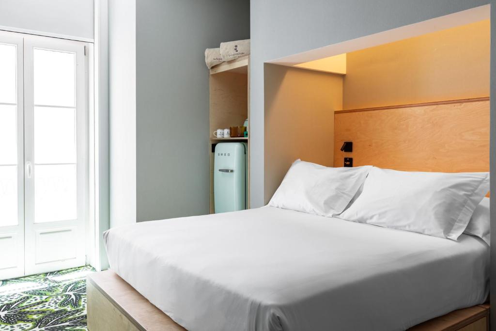 A bright double bedroom with a built-in wooden headboard and tall glazed doors.