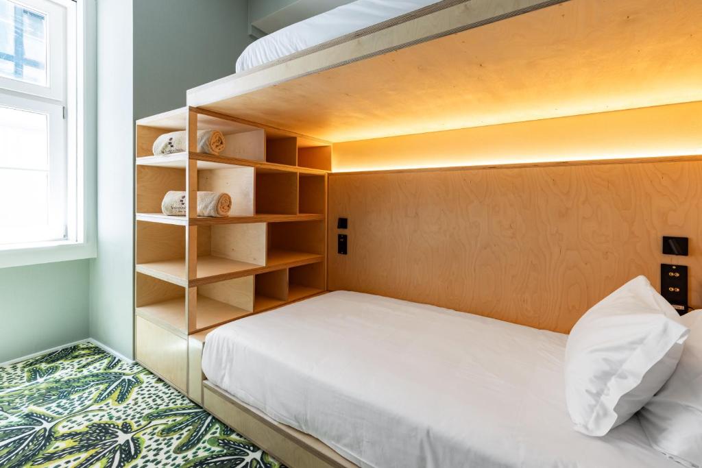 A built-in single bed beneath an upper bunk, with shelving and a window beside it.