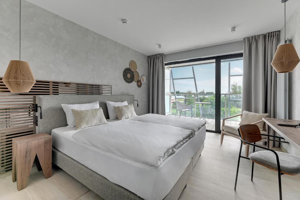 a bedroom with a large white bed and a desk at GRANO HOTEL Solmarina in Wiślinka