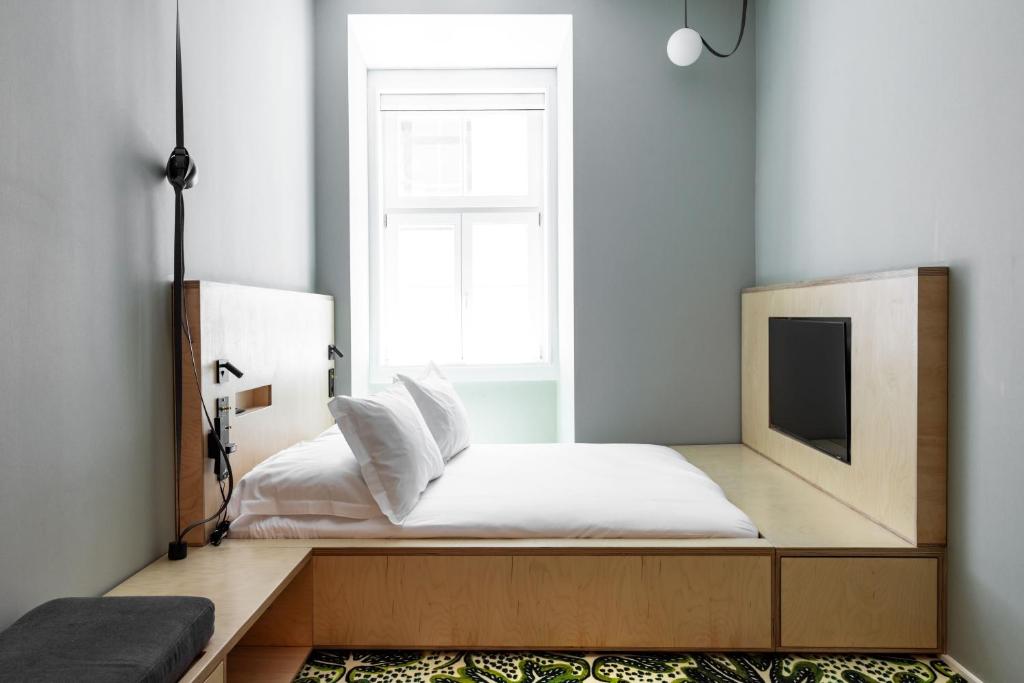 A narrow double bedroom with a wall-mounted television and a tall central window.