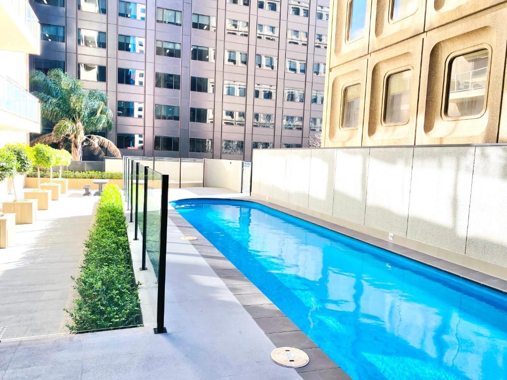 a swimming pool in front of a building at Bundled Bliss 2 bedroom Condo in Adelaide CBD in Adelaide