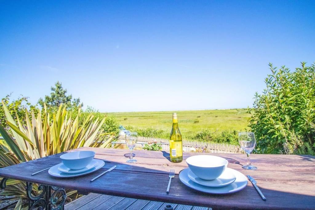 a wooden table with a bottle of wine and glasses at Ebb n Flow - 2 Bed - Nature Reserve & Beach Views in Winchelsea
