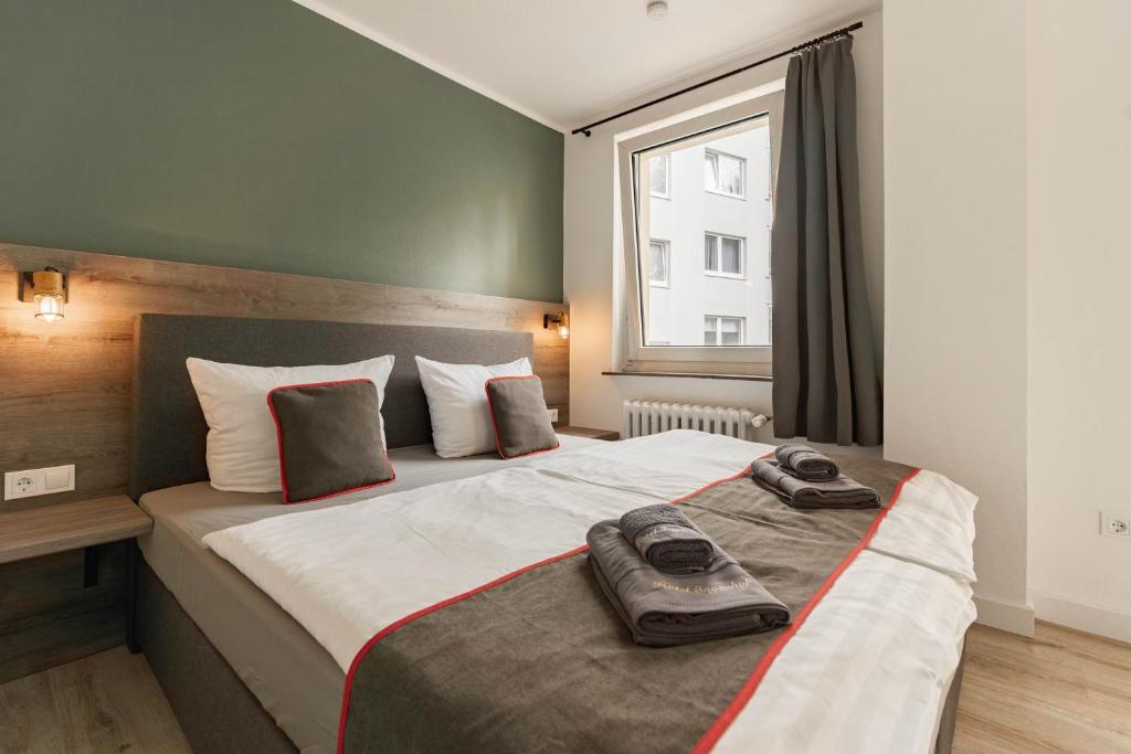 Un dormitorio con una cama grande con dos zapatos. en Hotel Enger Hof en Düsseldorf