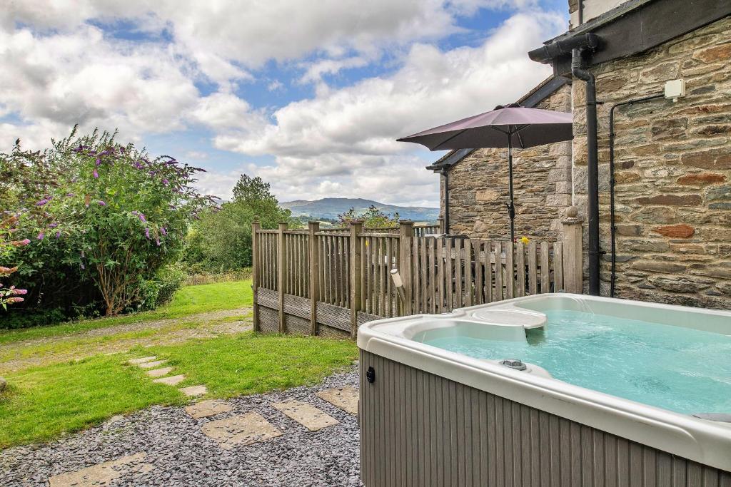 a hot tub in front of a house with an umbrella at Finest Retreats - Buzzards View in Eglwys-Fâch