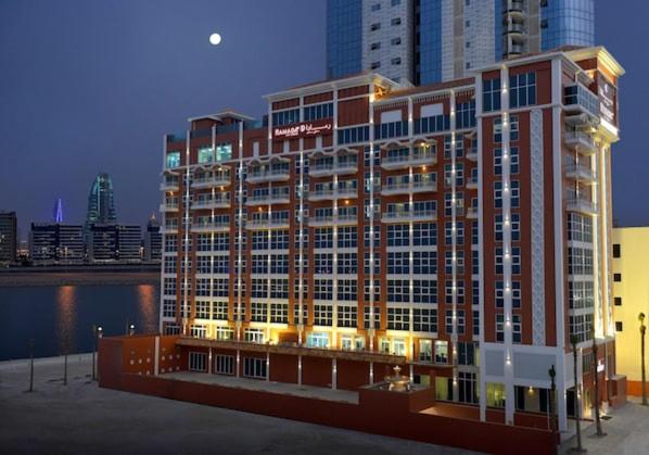 a large building with lights on in a city at Ramada by Wyndham Manama City Centre in Manama