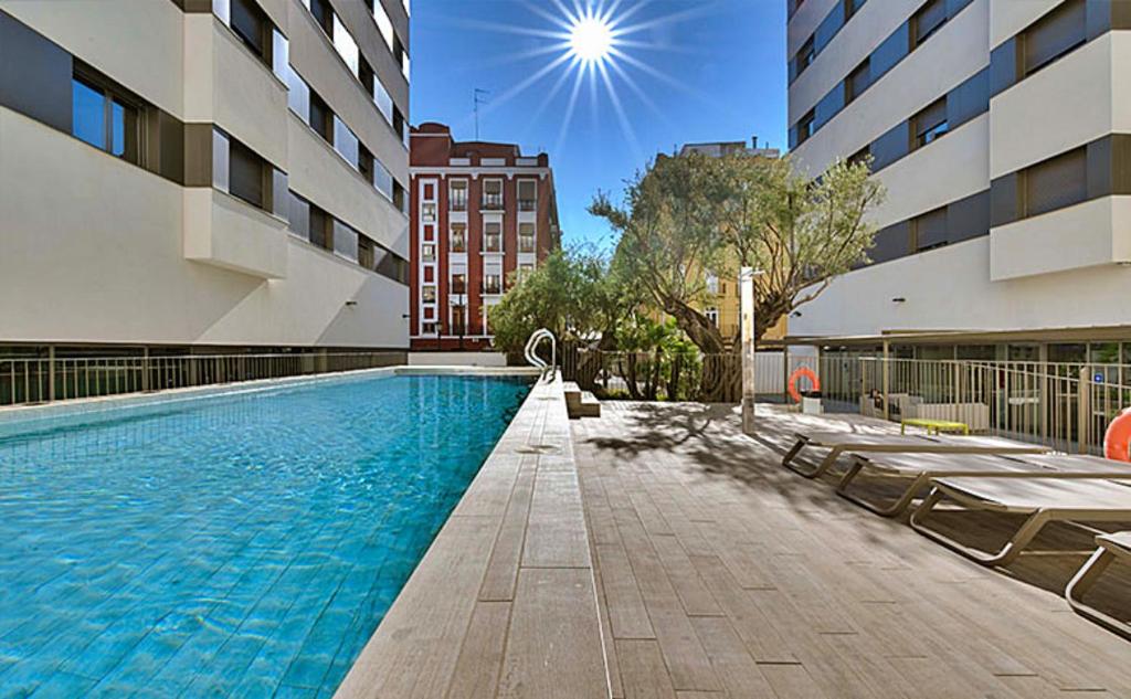 una piscina con sedie accanto a un edificio di Livensa Living Studios Valencia Marina Real a Valencia