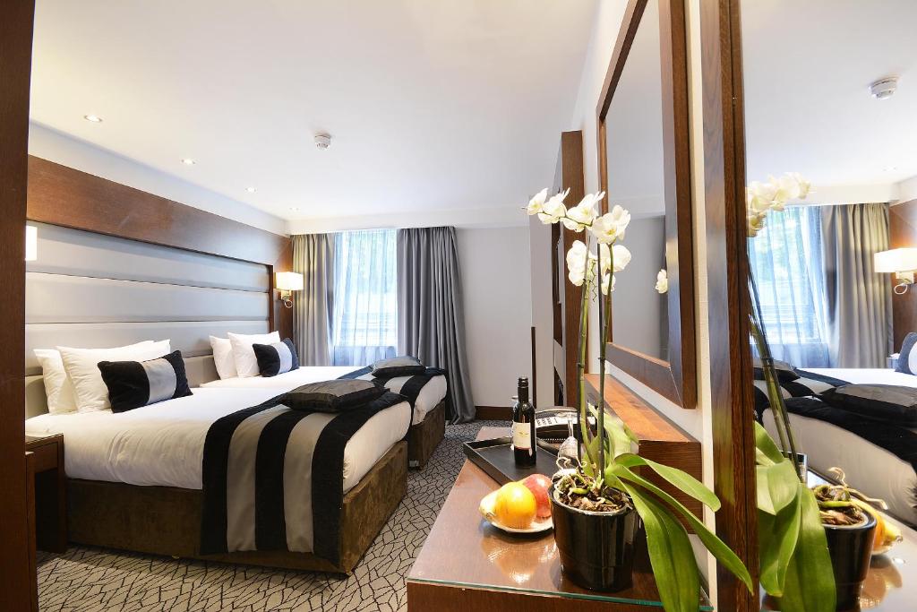 Habitación de hotel con 2 camas y espejo en Park Grand Paddington Court, en Londres