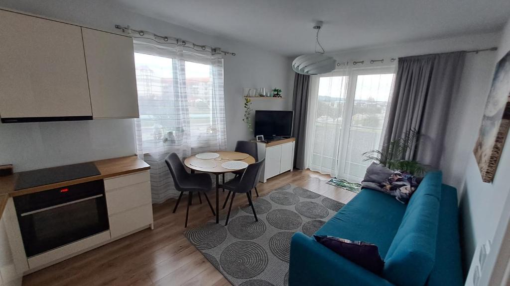 sala de estar con sofá azul y mesa en Nowiutki apartament z bezpłatnym parkingiem, en Rumia