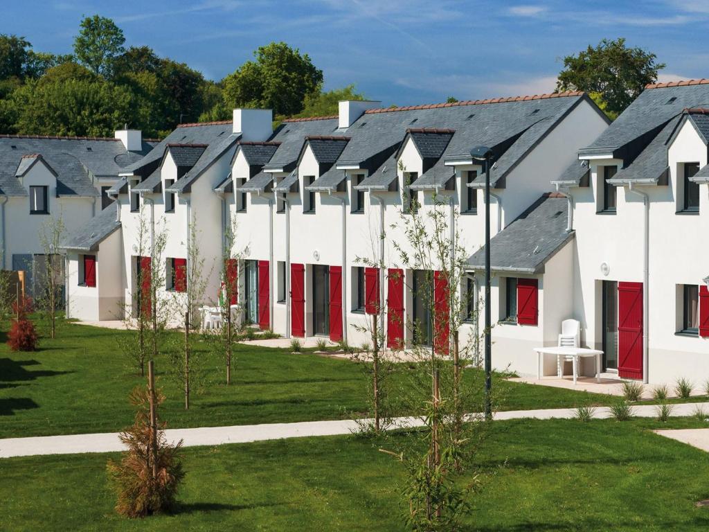 a row of white buildings with red doors at Comfortable holiday home close to a golf course in Brittany in Quéven