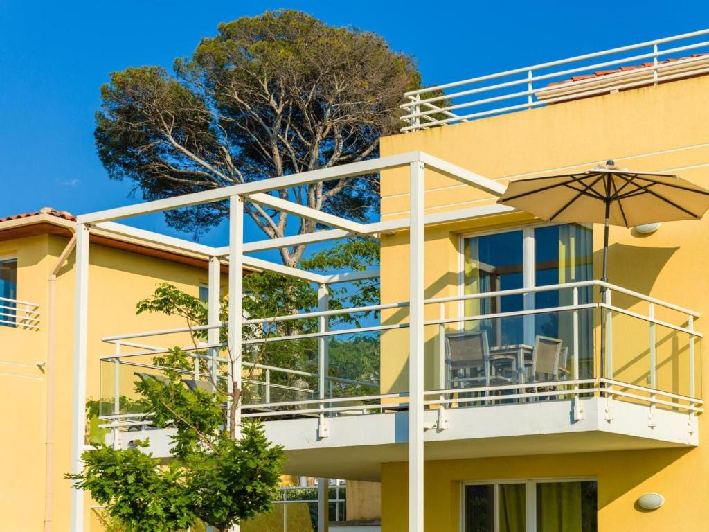 - un bâtiment jaune avec un balcon et un parasol dans l'établissement Apartment in Le Brusc near Sandy Beach, à Six-Fours-les-Plages