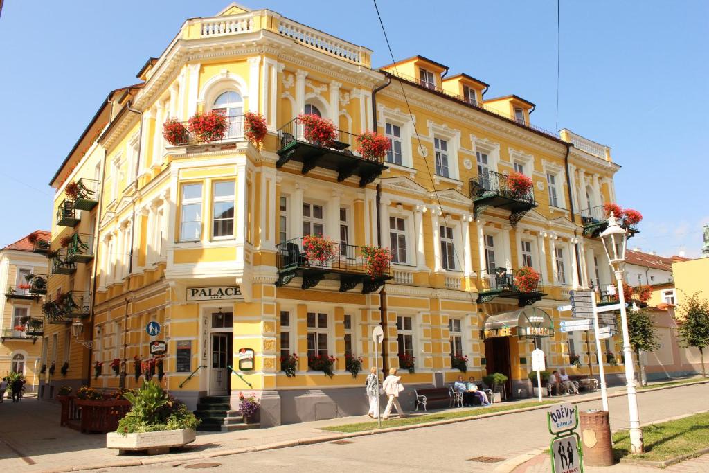 een geel gebouw met bloemen op de balkons in een straat bij LD PALACE Spa & Kur in Františkovy Lázně